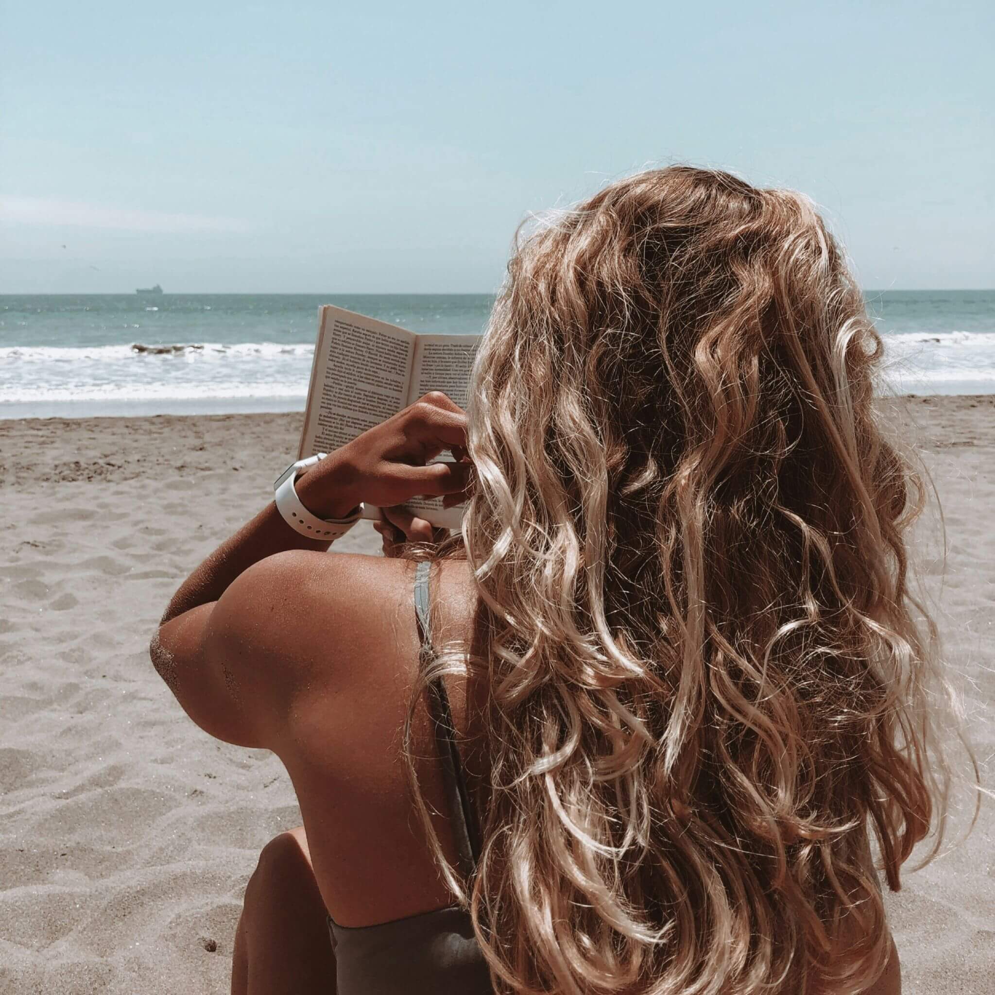 Lady Reading On The Beach Wearing Apple Watch With White Silicone Strap