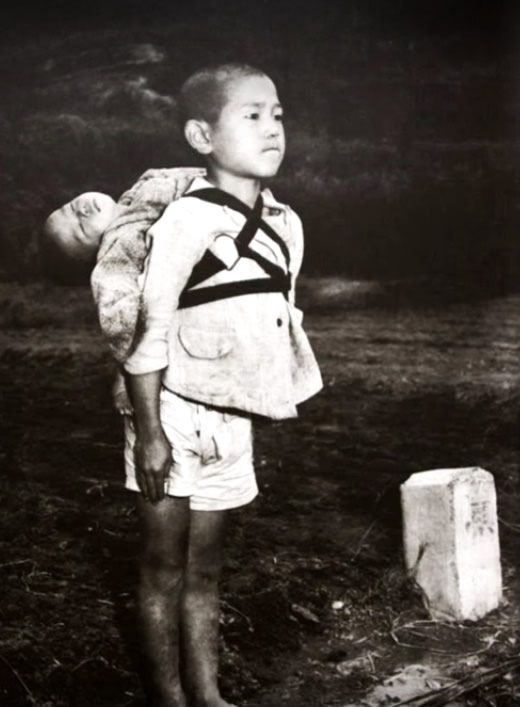 Japanese boy standing the body of his dead brother after Hiroshima attack